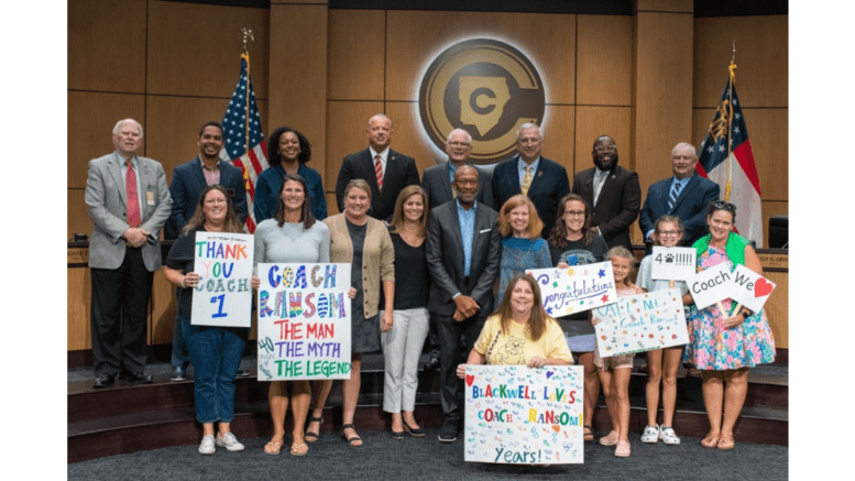 A group of elementary school students, administrators, and Cobb Board of Education members pose for photo