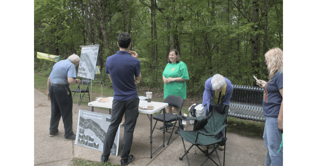 A group of people stand around a table set up on the Silver Comet Trail