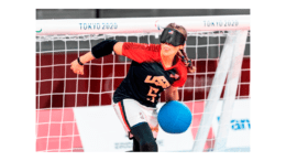 Woman at goal wearing mask blocks incoming ball