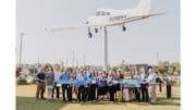 A large group of people hold a long blue ribbon with Cobb Commissioner JoAnn Birrell holding large scissors