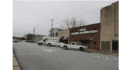 A scene along Broad Street in Austell GA, rows of storefront with diagonally parked cars