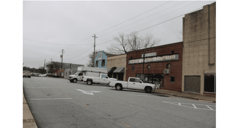 A scene along Broad Street in Austell GA, rows of storefront with diagonally parked cars