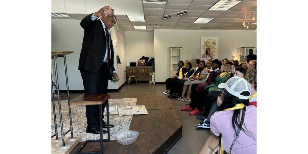 man in front of audience pours water into a bowl on floor)