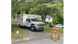 A GBI crime scene investigation truck behind yellow tape in the driveway of a small house