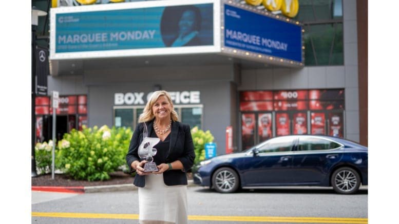 Stacey Chapman holding trophy in front of a theatre marquee