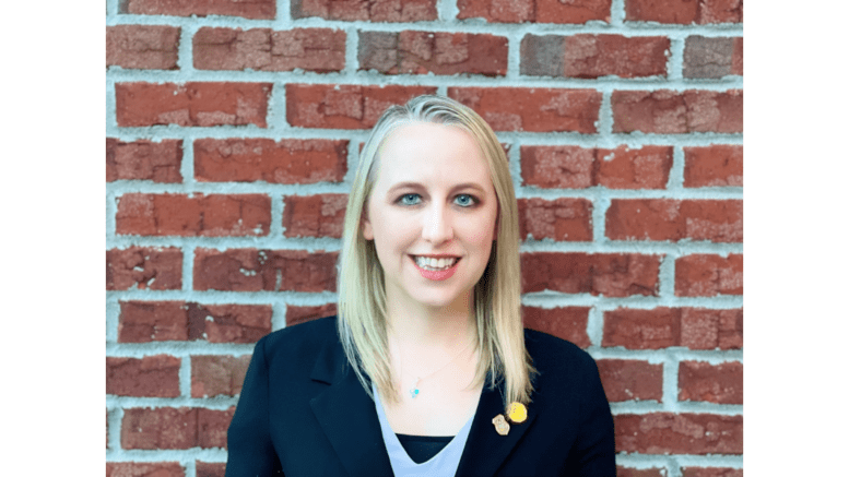 Kim Jewett standing in front of a brick wall.