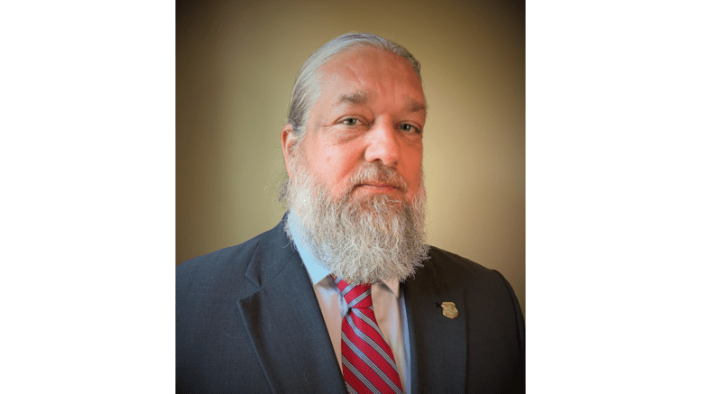 Klay Kilcrease bearded with a blue suit and striped tie.