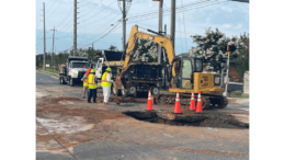 Men working around water main break with heavy equipment