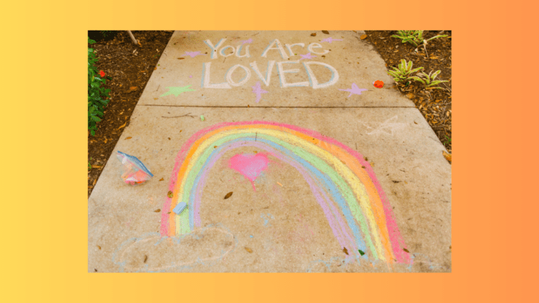 A sidewalk with a chalk rainbow and the words "You are loved"