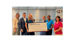 A group of five women and one man, two of the women holding up a large replica check