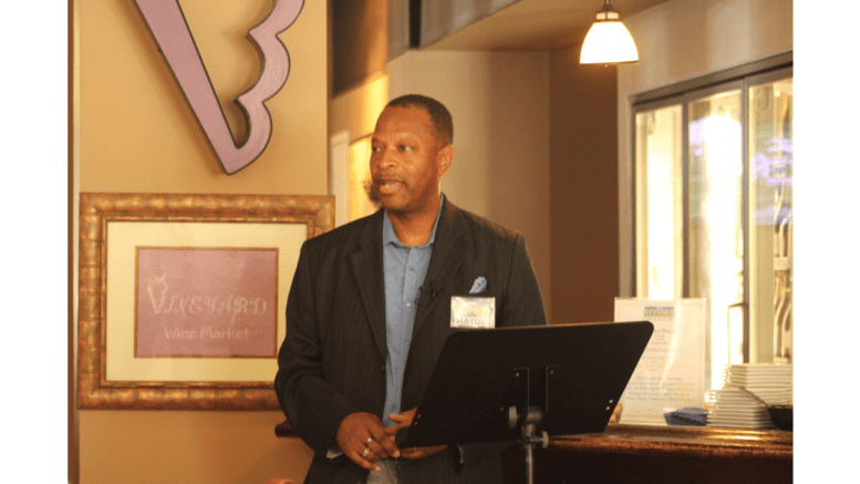 Ken Hymes speaking at a podium in a restaurant