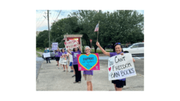 People waving signs protesting the banning of books by the Cobb County School District