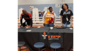 Three young people behind a table labeled "Tapp Middle School"