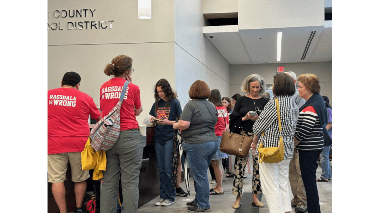 A group of people milling around the lobby during signup for public comment at the Cobb County School District