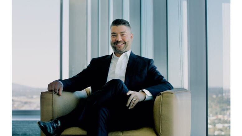 Kevin Redmon seated in a chair wearing a dark suit, white shirt, no tie