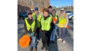 Men and women wearing yellow safety vests posing after cleanup of Queen Mill Road