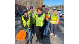 Men and women wearing yellow safety vests posing after cleanup of Queen Mill Road