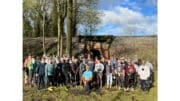 A large group of volunteers outdoors equipped for a cleanup