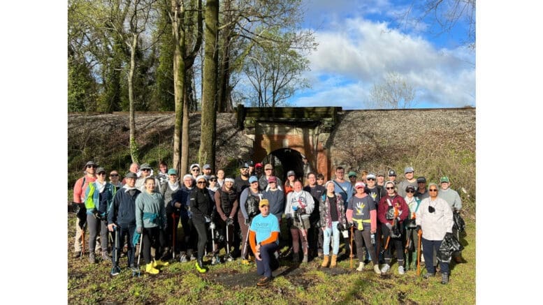 A large group of volunteers outdoors equipped for a cleanup