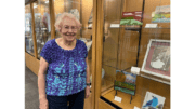 Ann Tewelow stands beside some of her fused art work