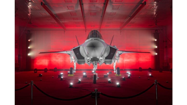 An F-35 fighter jet on display, bathed in red light