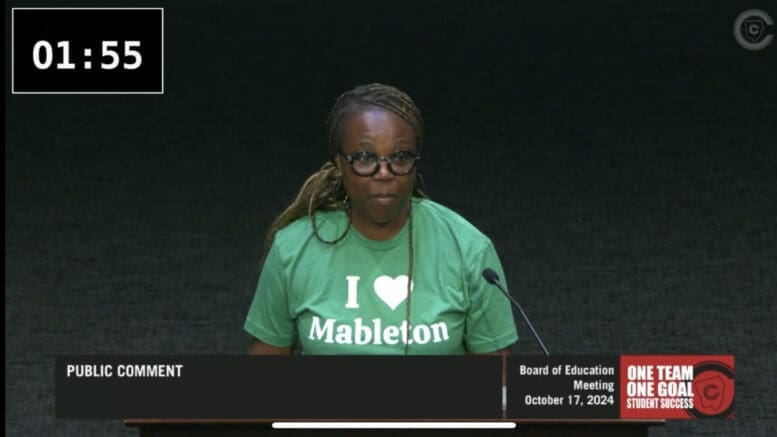 Cassandra Brown, wearing a green "I Love Mableton" t-shirt, speaks at the microphone durring the comment period at the Cobb County School District