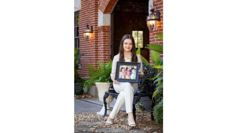 KSU student Ella Smith sits crosslegged with a photo of herself with grandmother