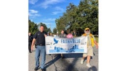 A police officer and a community volunteer hold a Faith & Blue banner