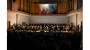 The Georgia Smyphony Orchestra in performance with a projection screen overhead