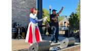 Woman in brightly colored red white and blue dress and man beside her with microphone