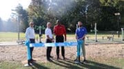 Four men cutting a ribbon in front of an exercise station