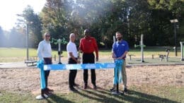 Four men cutting a ribbon in front of an exercise station