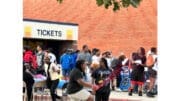 A crowd of people gathered in front of a brick building at a fall festival