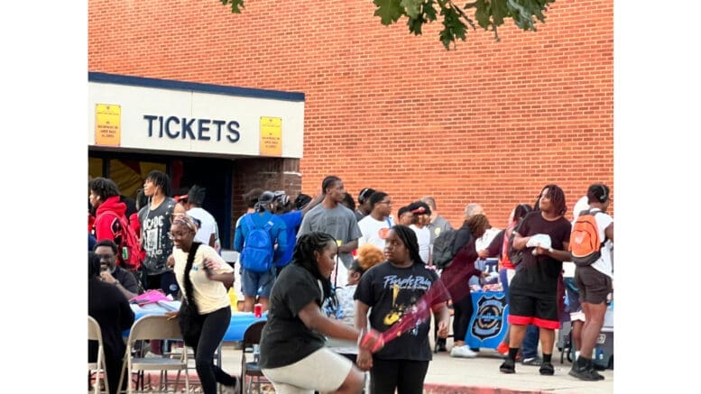 A crowd of people gathered in front of a brick building at a fall festival