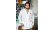 Kennesaw State University researcher Todd Pierson in white lab coat, leaning against counter in biology lab