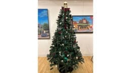 A decorated Christmas tree with a skull on top, described as a Gothic Christmas Tree