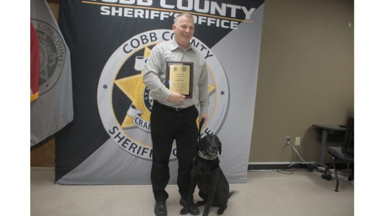 Retired Sgt. Ronnie Kite poses with retired drug dog K-9 Krush, a black lab