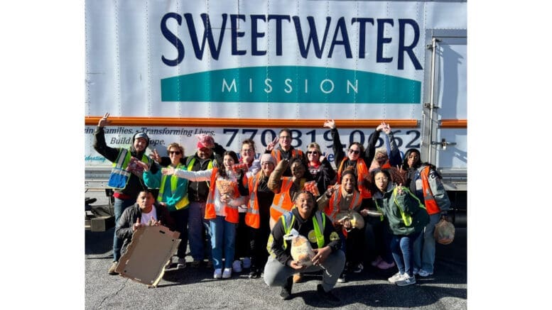 Group photo of volunteers at a Sweetwater Mission food distribution in Mableton standing in front of a large Sweetwater Mission semi trailer