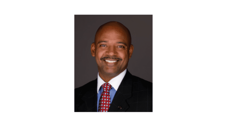 Headshot of KSU professor Aaron Adams, smiling, wearing a suit and tie