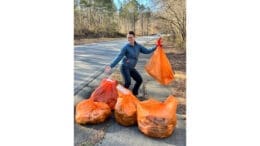 Mableton Councilwoman Patricia Auch displays orange bags of trash from a littler cleanup