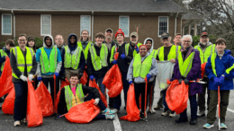 A group photo of Scout Troop 22 and other volunteers, wearing yellow safety vests and holding orange litter bags