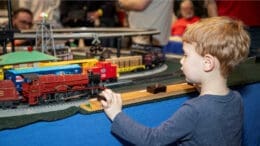 A child gazes in fascination at a model train display