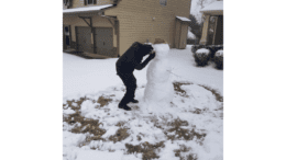 A man puts the orange nose on a snowman