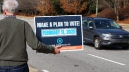 Man holding a Make a Plan to Vote sign