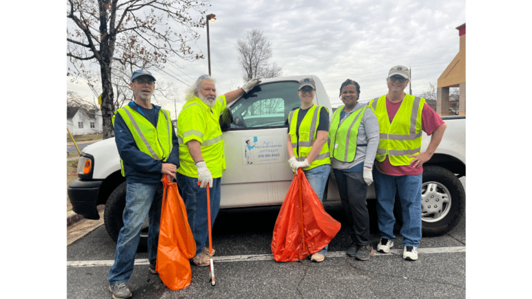 Group shot of five volunteer during a cleanup on Hicks and Bates road. The volunteers are wearing safety vests