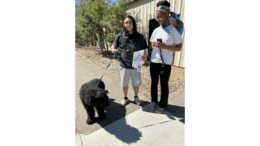 A couple with their newly adopted black poodle