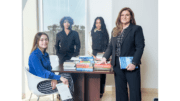 A female professor with three young women students pose for a group shot around a table