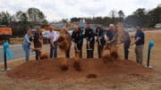 A group of people, some in public safety uniforms, throw dirt with shovels at the groundbreaking for Kennesaw's new Public Safety Facility