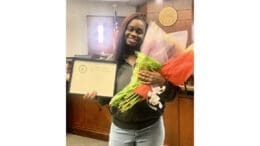 A smiling woman holds flowers and a certificate from Cobb Mental Health Court