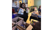 A smiling woman holds up a "blessing bag" with items to distribute to those in need